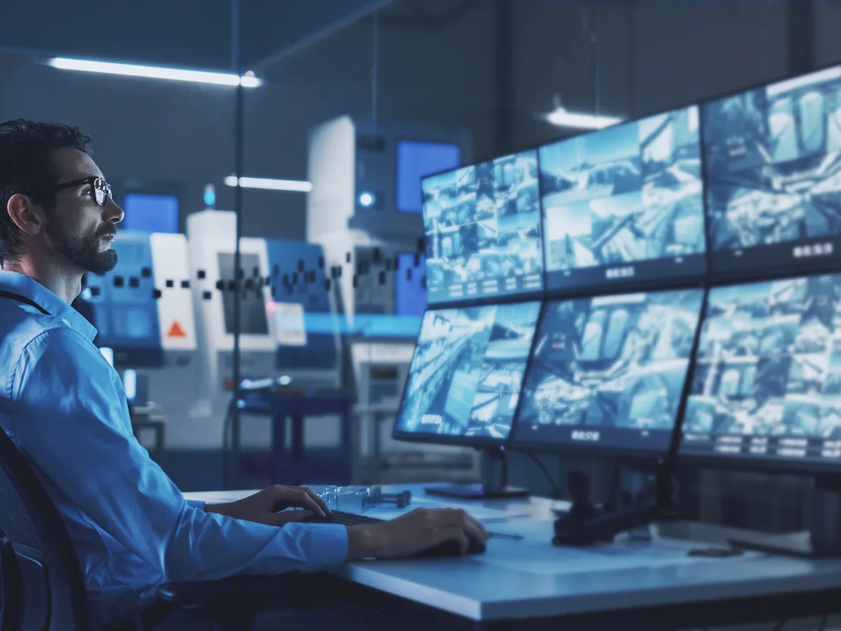 Man watching multiple screens with security video in real-time to provide managed XDR services.