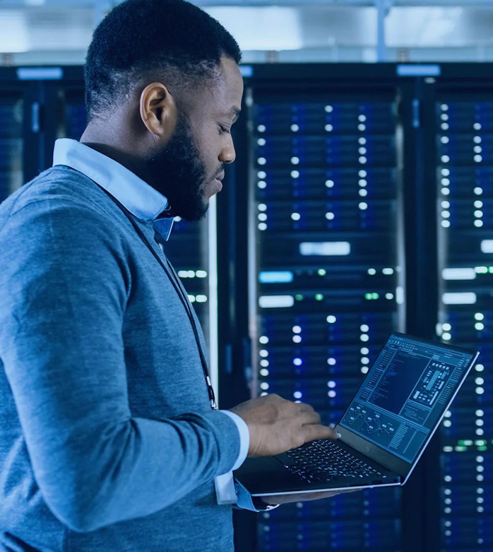 Man using a computer inside a DRaaS facility surrounded by data storage equipment.